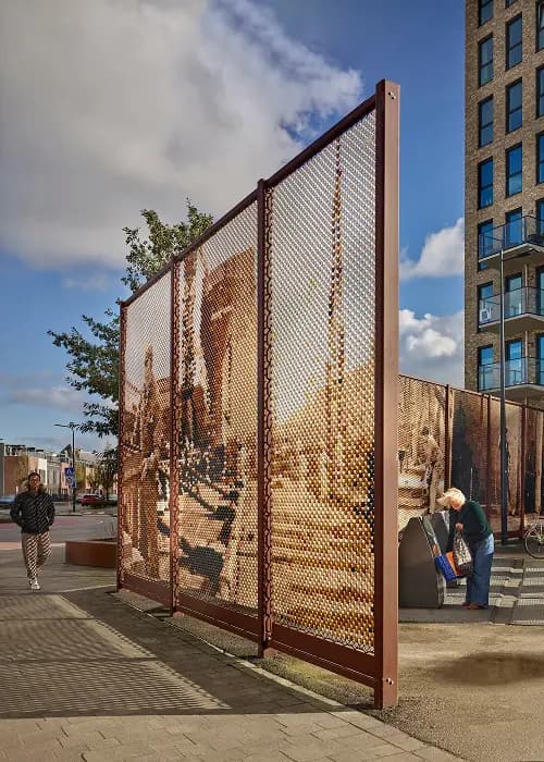 Roestbruin designhek van Redfort met fotomotief in een straat naast een woongebouw